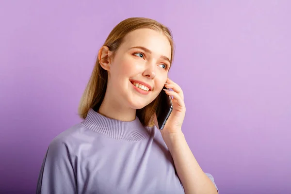 Fiatal gyönyörű nő beszél mobiltelefon okostelefon elszigetelt felett lila háttér. Boldog mosolygós kaukázusi tinédzser lány használja mobiltelefon — Stock Fotó