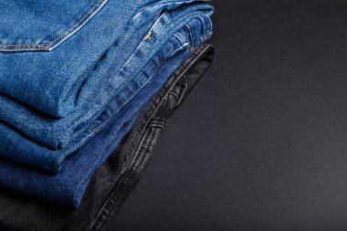 Siyah arka planda kopyalanmış kot pantolon yığını. Kot pantolon yığınından yapılmış çerçeve.
