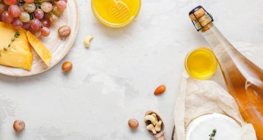 Açık gri kırsal beton arka planda şarap kompozisyonu. Çerçevesi pembe şarap şişesi peynir ve üzüm balı. Camembert peyniri, romantik yemek için şarap barı atıştırmalıkları. Uzun web pankartı