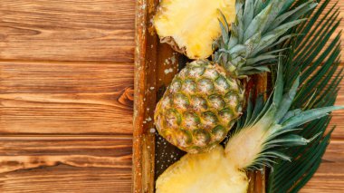 Olgun Ananas. Tropikal yaz meyveli ananas yarımları ve tüm ananaslar kahverengi siyah masa üzerinde ahşap kutuda. Kopyalama alanı olan uzun web pankartı üst görünümü