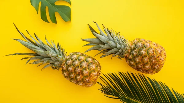Piñas y hojas de palma sobre fondo veraniego de color amarillo. Piñas tropicales de verano frutas planas composición laica. Banner web largo — Foto de Stock