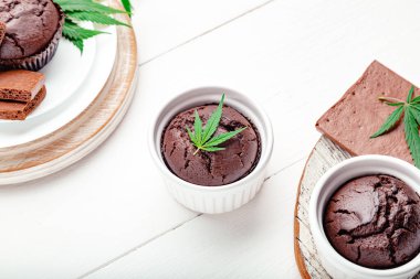 Marihuana çikolatalı kek ve kenevir, ot CD 'si bırakır. Tıbbi marihuana, tatlı olarak kenevir ilacı. Ahşap beyaz masada marihuana ile pişirme kabında ot keki pişirmek.