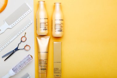 L 'oreal Profesnel Paris Serie Expert loreal besleyici saç ürünleri makas tarakları ve kuaför aletleri. Renkli arkaplanda Loreal saç şampuanı. Altın kozmetik şişeleri. düz yat