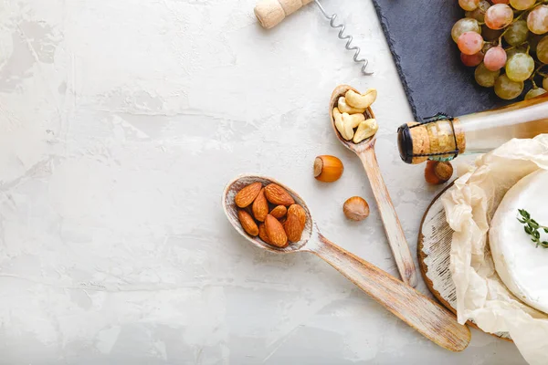 Cashews and almonds nuts in wooden spoons as appetizers snack set for wine and Cheese on Stone Light gray table with copy space. Rustic wine snacks