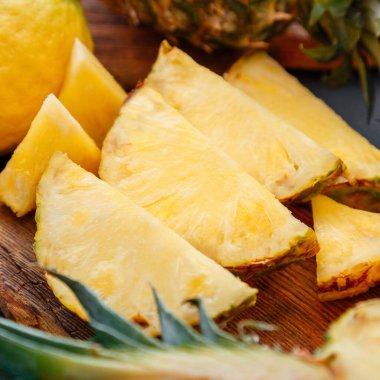 Kesme tahtasında dilimlenmiş ananas. Yaz meyvesi dilimlenmiş ananas dilimleme işlemi mutfakta koyu arka planda. Kare