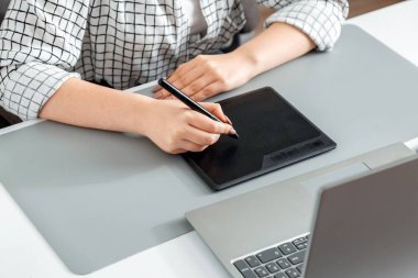 Profesyonel ekipmanlarla çalışan yaratıcı tasarımcı. Ev işyerinde dijital tablet dizüstü bilgisayar çizen kadın el tasarımcısı. Eldeki stil kalem grafik tabletine çizer.