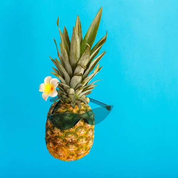 Cara masculina de abacaxi engraçado em flor de plumeria de óculos de sol verde. Frutas tropicais de verão levitando abacaxi criativo de verão na cor azul fundo de verão. Retrato de estúdio quadrado — Fotografia de Stock