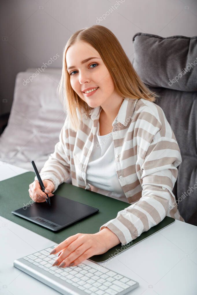 Portrait of Young Smiling artist graphic designer. Caucasian blonde woman drawing on graphic tablet by Stylus pen using pc Computer at home office interior. Freelance designer work on workspace.