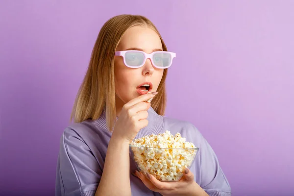 映画館で3D映画を見て映画メガネの若い女性。笑顔ティーン女の子ムービービューアで眼鏡食べるポップコーン絶縁上の紫の色の背景とともにコピースペース. — ストック写真