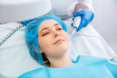 Cilt bakımı için yapılan Darsonval kozmetoloji prosedürü sırasında kadınlar kozmetolog dermatolog muayenesinde yatarlar. Güzellik aleti, güzellik salonunda yüz bakımı için doktor elinde.