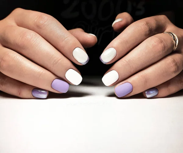 Gentle white-purple gel polish. Women's hands with professional manicure and beautiful design.