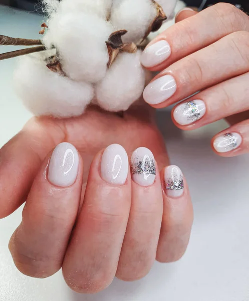 White nails with sequins and a silver crown design. White shiny gel polish on round short nails