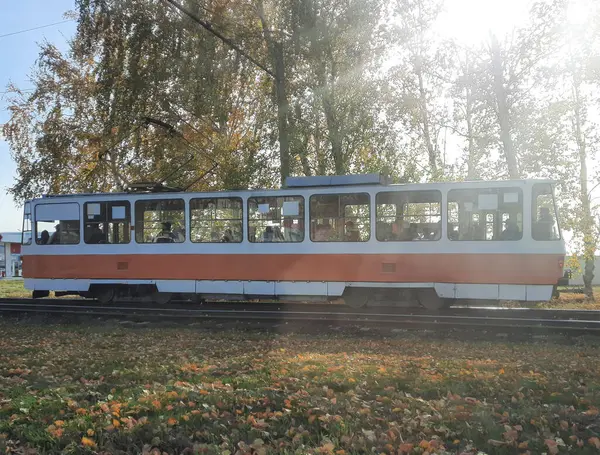 Yolcularla dolu tramvay güneşli bir havada şehirden geçer.