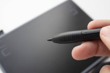 Bir insan grafik tabletine resim çizer. El dokunmatik kalemi tutar. Tasarımcı ve sanatçı için kablolu grafik tablet. Adam grafik tableti üzerinde çalışıyor..