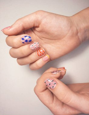 Kamuflaj jeli ojesi, çok renkli tasarımı ve farklı desenleri var. Manikür bej rengi ve desenleri var. Çivilerin üzerini geometrik desenlerle kaplamak.