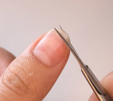 Bir insan tırnaklarını küçük bir makasla keser. Erkek manikürü. Bir adam kocaman bir çiviyi kesiyor.