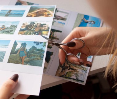Bir kadın yakın planda insanlarla fotoğraf çektirir. Bir kız basılı fotoğraf çekmek için makas kullanıyor. Albüm için. Bir insan diğer fotoğrafların arka planına karşı elinde bir polaroid fotoğraf tutar..