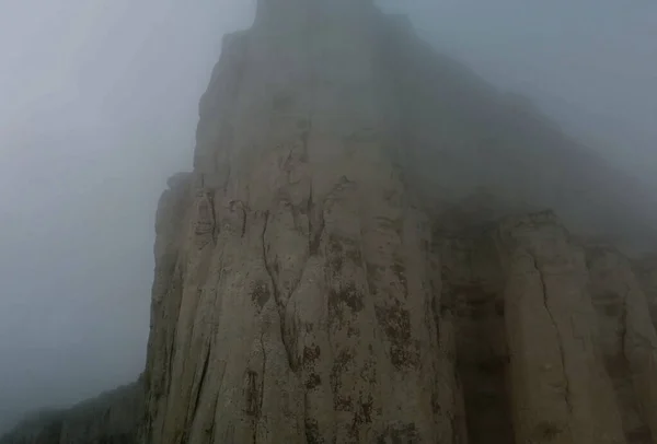 霧のような暗い空を持つ急な崖 山と谷には濃くて不気味な霧がかかっている — ストック写真