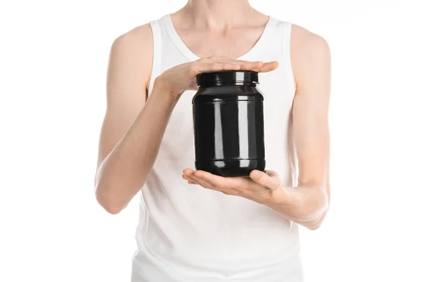 Bodybuilding and Sports theme: a thin man in a white T-shirt and jeans holding a plastic jar with a protein isolated on a white background in studio — Stock Fotó