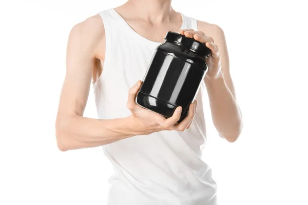 Bodybuilding and Sports theme: a thin man in a white T-shirt and jeans holding a plastic jar with a protein isolated on a white background in studio — Stock Fotó