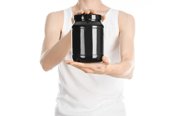 Bodybuilding and Sports theme: a thin man in a white T-shirt and jeans holding a plastic jar with a protein isolated on a white background in studio — ストック写真