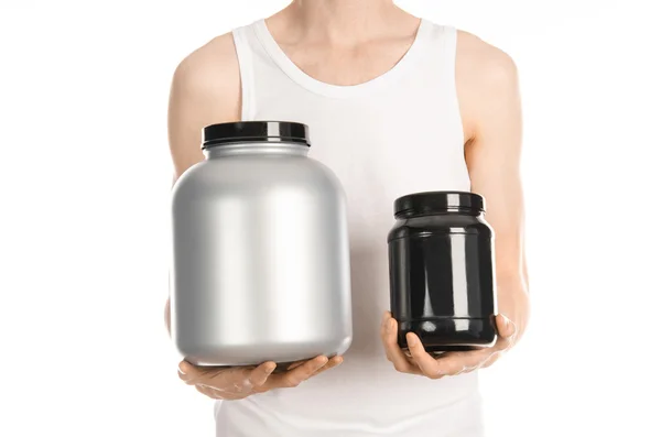 Bodybuilding and Sports theme: a thin man in a white T-shirt and jeans holding a plastic jar with a protein isolated on a white background in studio — Zdjęcie stockowe