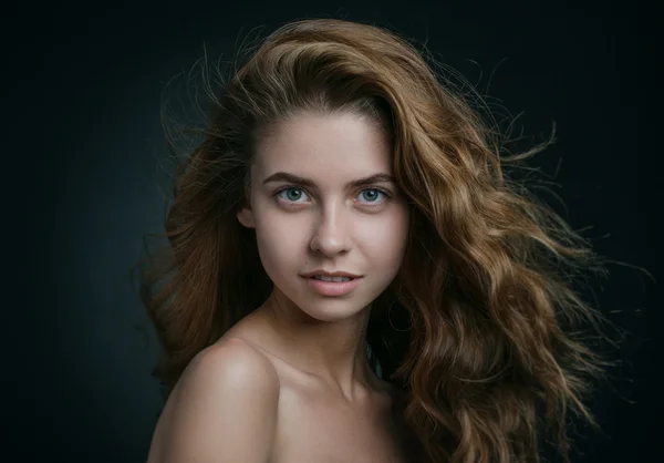 Dramatische portret van een meisje thema: portret van een mooi meisje met vliegende haren in de wind tegen een achtergrond in de studio — Stockfoto