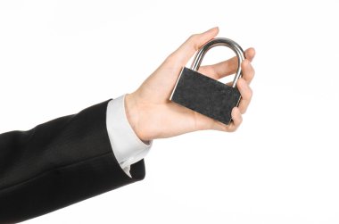 Protection and business theme: a man in a black suit holding a metal padlock isolated on a white background in studio