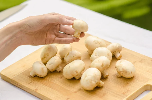 Funghi e cibo tema: l'uomo prepara funghi porcini su una tavola di legno su uno sfondo di erba verde in estate — Foto Stock