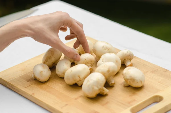 Funghi e cibo tema: l'uomo prepara funghi porcini su una tavola di legno su uno sfondo di erba verde in estate — Foto Stock