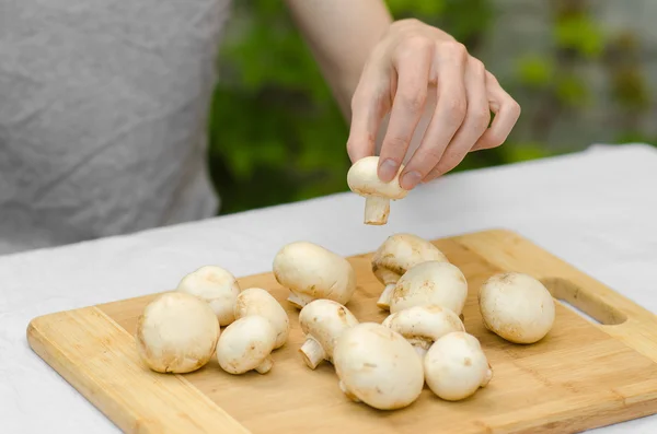 Funghi e cibo tema: l'uomo prepara funghi porcini su una tavola di legno su uno sfondo di erba verde in estate — Foto Stock