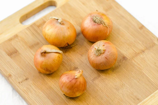 Food and picnic topic: onion lying on a wooden board in the background of green grass — Stock Photo, Image