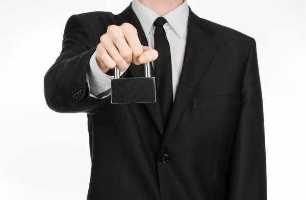 Tema protezione e business: un uomo in abito nero con un lucchetto di metallo isolato su sfondo bianco in studio — Foto Stock