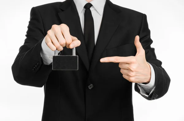 Protection and business theme: a man in a black suit holding a metal padlock isolated on a white background in studio — 스톡 사진