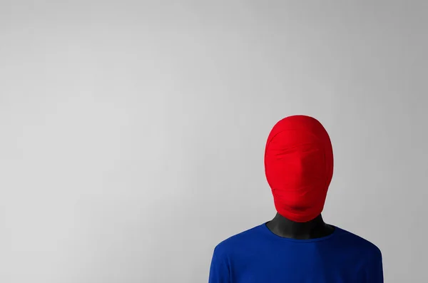 Thema Surrealismus: Mann in blauer Jacke mit rotem Tuch um den Kopf steht in der Ecke auf grauem Hintergrund — Stockfoto