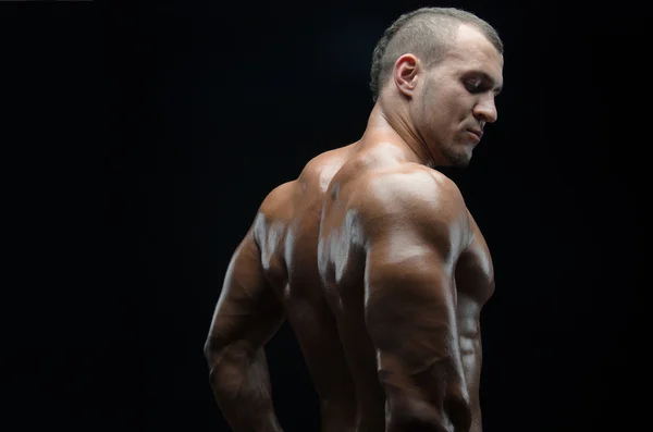 Bodybuilder and strip theme: beautiful with pumped muscles naked man posing in the studio on a dark background — Stock Photo, Image