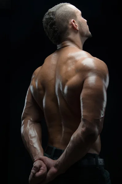 Bodybuilder en strip thema: mooi met naakte man gepompt spieren poseren in de studio op een donkere achtergrond — Stockfoto