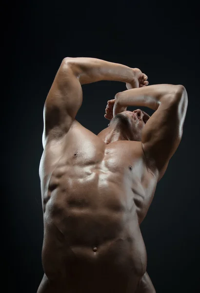 Bodybuilder and strip theme: beautiful with pumped muscles naked man posing in the studio on a dark background — Stock Photo, Image