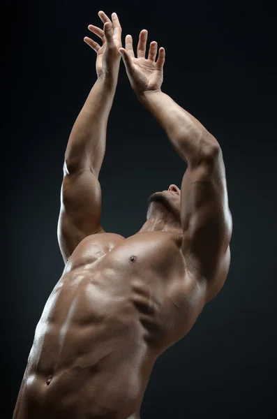 Бодибилдер и стрип тема: красивая с накачанными мышцами голый мужчина позирует в студии на темном фоне — стоковое фото