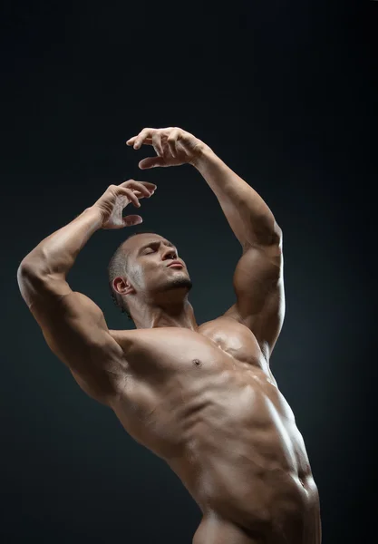 Bodybuilder and strip theme: beautiful with pumped muscles naked man posing in the studio on a dark background — Stock Photo, Image