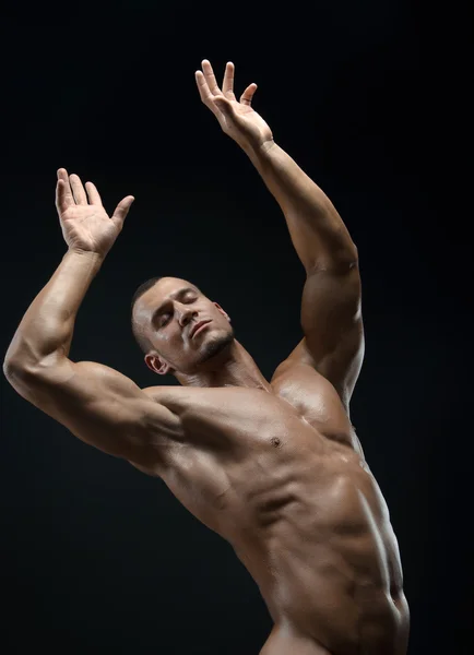 Bodybuilder and strip theme: beautiful with pumped muscles naked man posing in the studio on a dark background — Stock Photo, Image