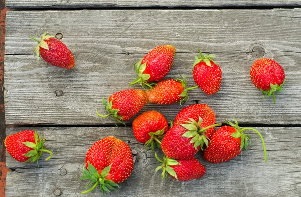 Summer berries topic: Ripe red strawberries bunch of lies on gray wooden table in the garden, view from above