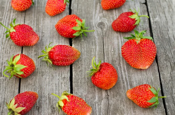 Summer berries topic: Ripe red strawberries bunch of lies on gray wooden table in the garden, view from above