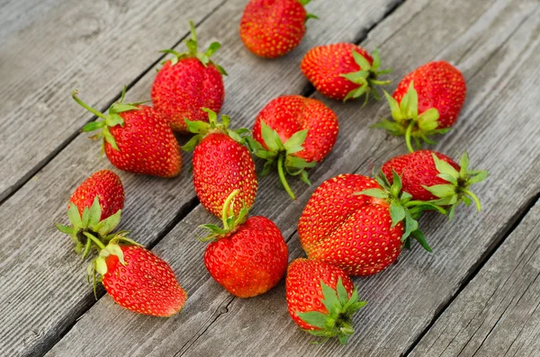 Summer berries topic: Ripe red strawberries bunch of lies on gray wooden table in the garden, view from above