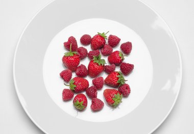 Restoran ve diyet konu sağlıklı beslenme: çilek ve ahududu beyaz plakalı beyaz bir tablo studio üst görünümünde izole