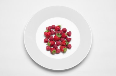 Restoran ve diyet konu sağlıklı beslenme: çilek ve ahududu beyaz plakalı beyaz bir tablo studio üst görünümünde izole