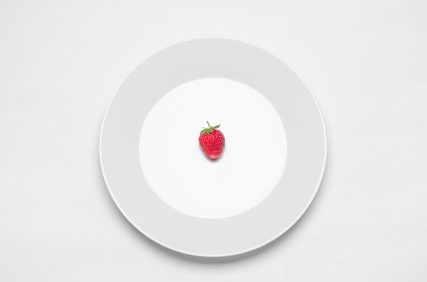 Healthy eating in the restaurant and diet Topic: white plate with a strawberry lying on a white table in the studio isolated top view