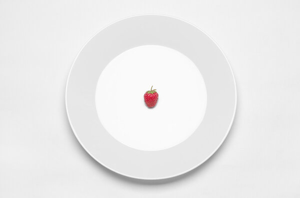 Тема: белая тарелка с клубникой, лежащей на белом столе в студии
