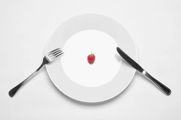 Zdrowe odżywianie w restauracji i dieta temat: biała płyta z truskawką i metalowym nożem i widelcem leżącego na białym stole w Studio z widokiem na góry — Zdjęcie stockowe