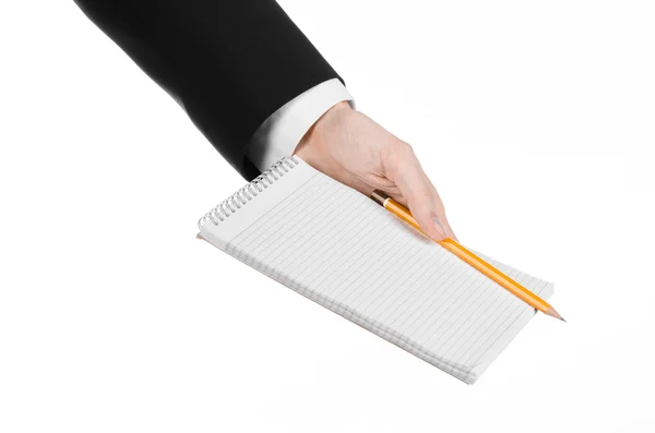 Tema business e reporter: la mano di un giornalista in abito nero che tiene un quaderno con una matita su sfondo bianco isolato — Foto Stock